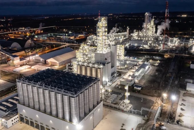 Aerial nighttime view of an illuminated industrial complex with grain silos and chemical processing plants in a rural area
