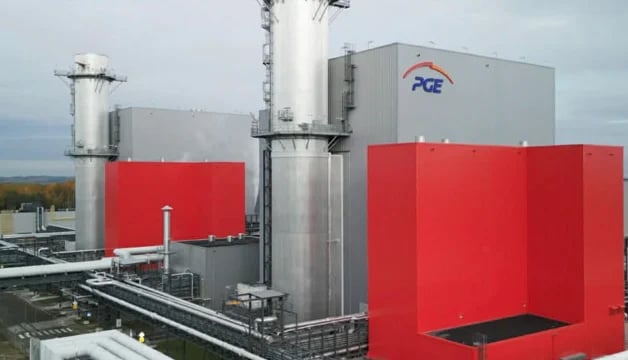 Industrial facility with red and gray tanks, metal piping, and ACE branded structure in rural setting